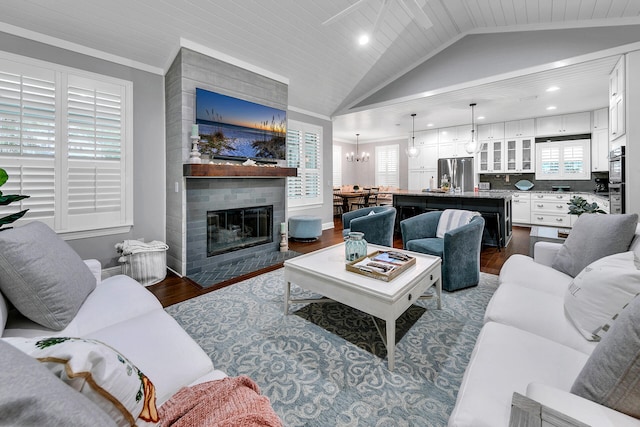 living room with a healthy amount of sunlight, an inviting chandelier, a brick fireplace, and dark hardwood / wood-style floors