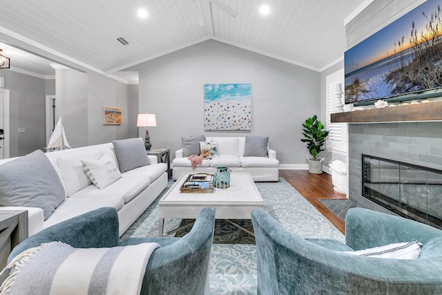 living room featuring hardwood / wood-style floors, lofted ceiling, ornamental molding, and a fireplace