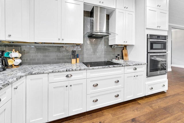 kitchen with backsplash, double oven, wall chimney range hood, and dark hardwood / wood-style flooring