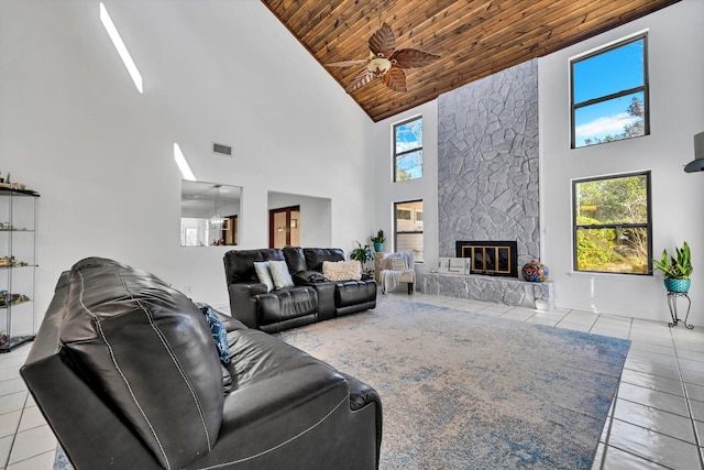 living room featuring high vaulted ceiling, a stone fireplace, and wood ceiling