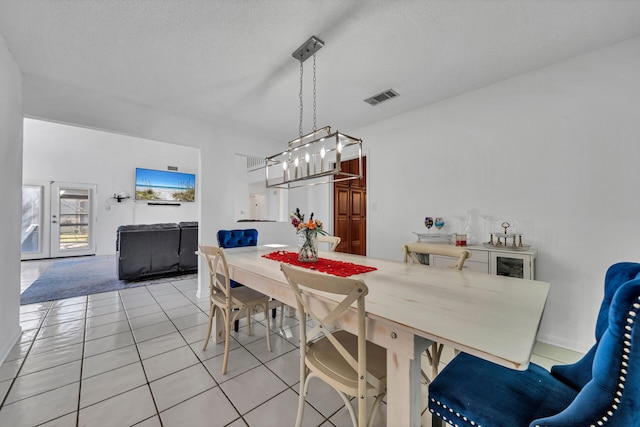 tiled dining area with a textured ceiling and an inviting chandelier