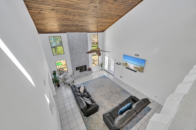 tiled living room featuring a large fireplace, ceiling fan, high vaulted ceiling, and wooden ceiling