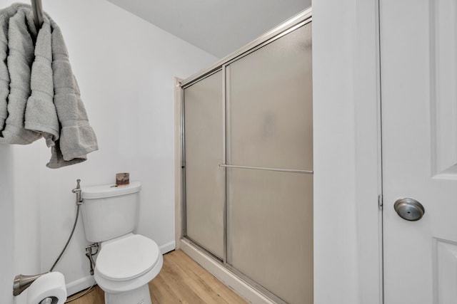 bathroom featuring an enclosed shower, hardwood / wood-style flooring, and toilet