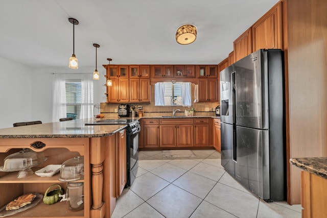 kitchen with a wealth of natural light, stainless steel fridge with ice dispenser, hanging light fixtures, and black electric range