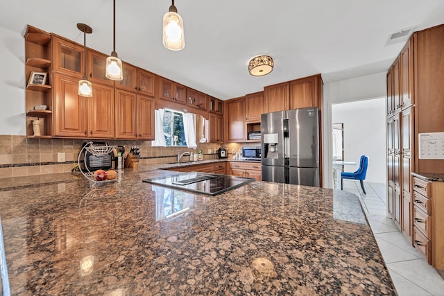 kitchen featuring tasteful backsplash, appliances with stainless steel finishes, dark stone countertops, and decorative light fixtures