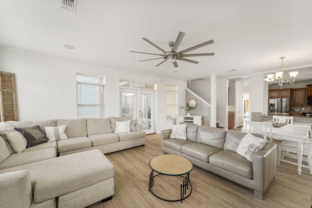 living room with ceiling fan with notable chandelier, light wood-type flooring, and ornamental molding