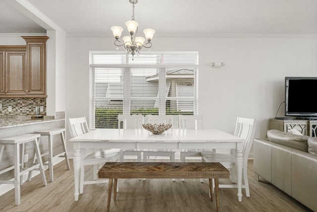 dining room with a chandelier, ornamental molding, and light wood-type flooring