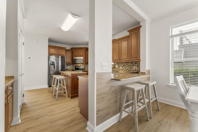 kitchen featuring backsplash, a kitchen breakfast bar, stainless steel appliances, and plenty of natural light