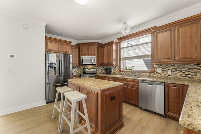 kitchen featuring a kitchen island, stainless steel appliances, tasteful backsplash, sink, and light wood-type flooring