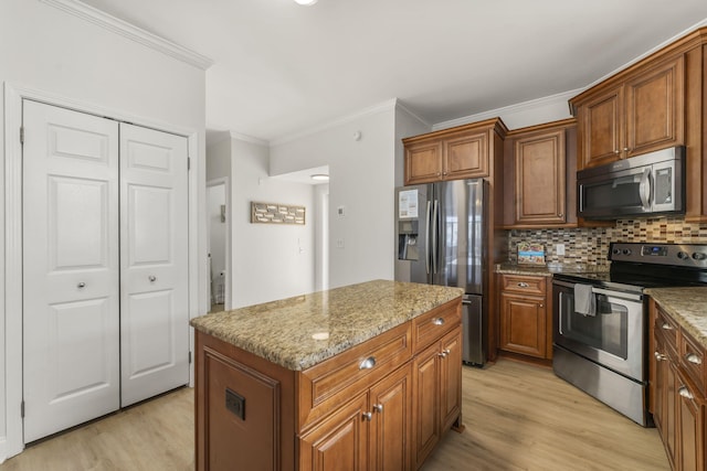 kitchen featuring light stone counters, appliances with stainless steel finishes, a center island, tasteful backsplash, and light hardwood / wood-style flooring