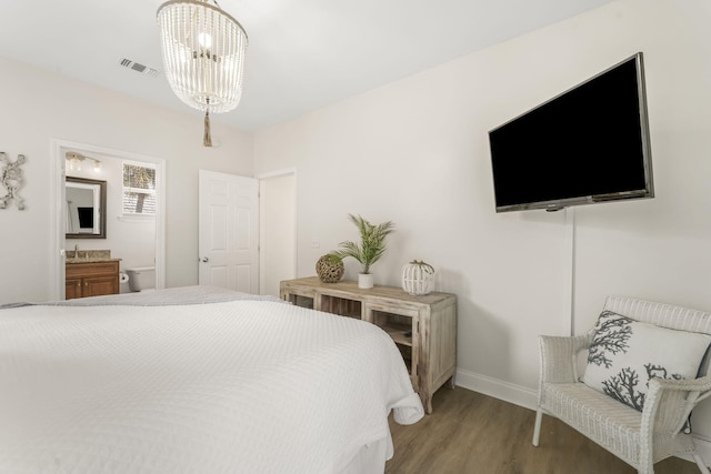 bedroom with sink, light hardwood / wood-style floors, an inviting chandelier, and connected bathroom