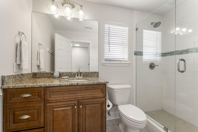 bathroom featuring tile flooring, vanity, toilet, and a shower with shower door