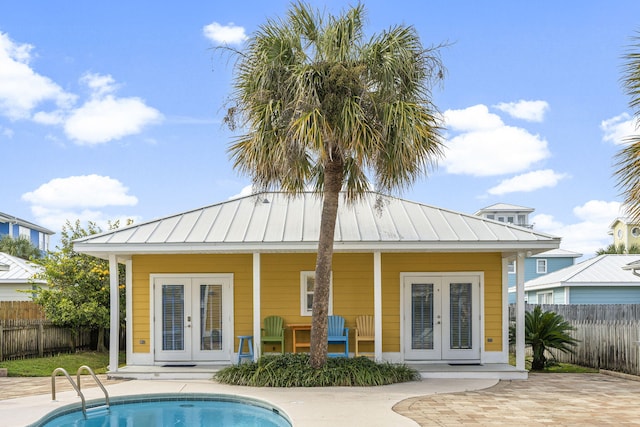 rear view of house featuring french doors and a fenced in pool