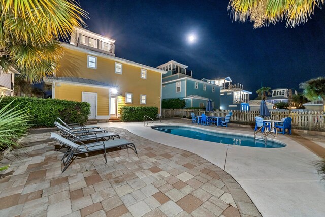 pool at night featuring a patio area