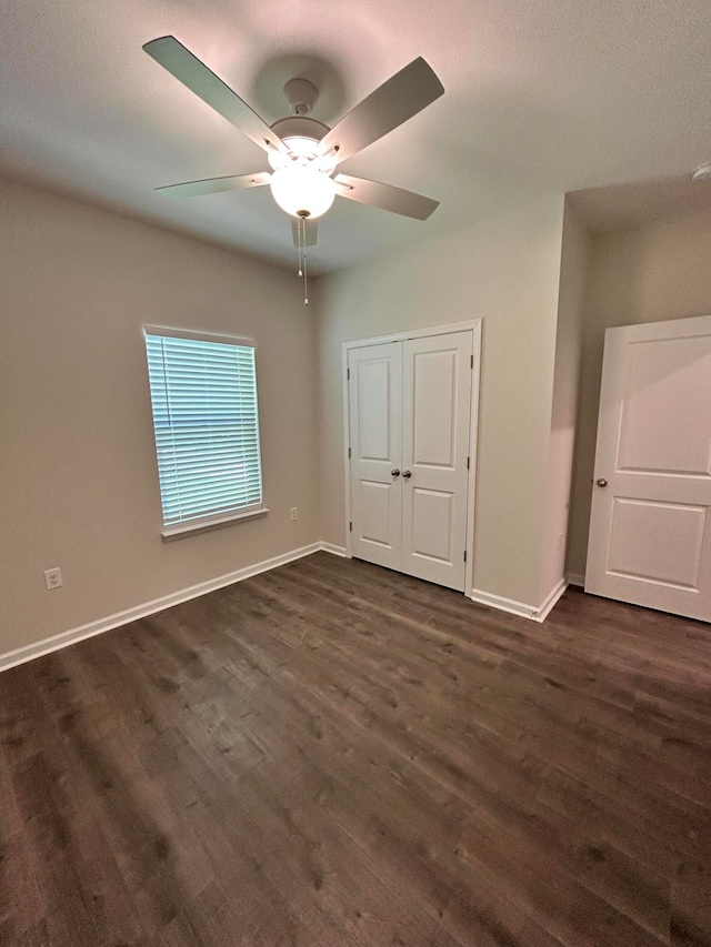 unfurnished bedroom with ceiling fan, dark hardwood / wood-style flooring, and a closet