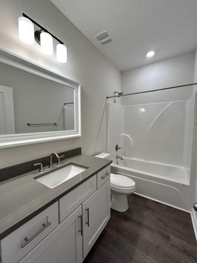 full bathroom featuring toilet, vanity, hardwood / wood-style flooring, and  shower combination