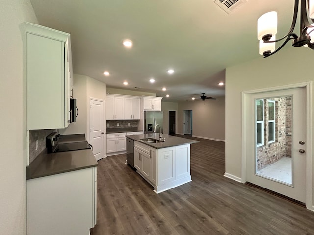 kitchen with tasteful backsplash, dark wood-type flooring, stainless steel appliances, sink, and a center island with sink