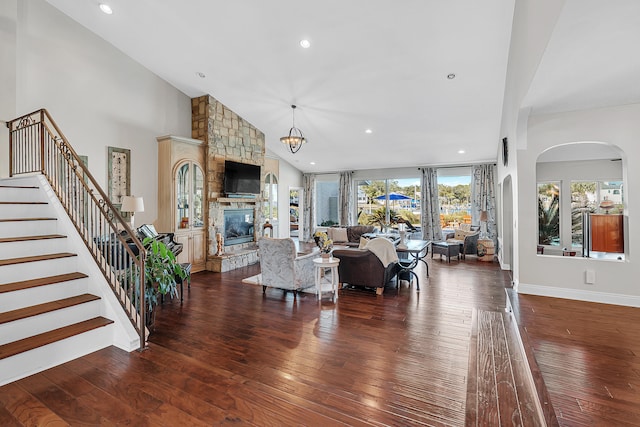 living room with a chandelier, a fireplace, dark hardwood / wood-style flooring, and high vaulted ceiling