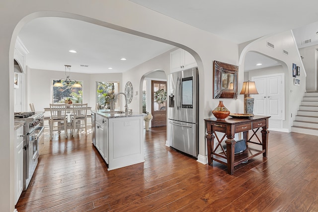 kitchen featuring white cabinetry, stainless steel appliances, a kitchen island with sink, and pendant lighting