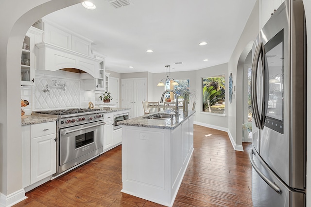 kitchen featuring sink, light stone counters, an island with sink, stainless steel appliances, and white cabinets