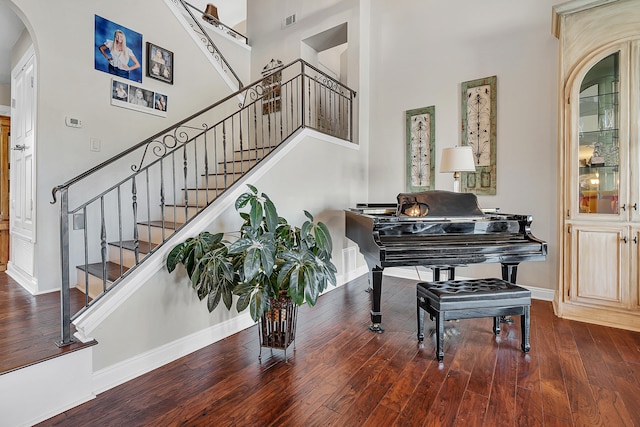 staircase with a high ceiling and wood-type flooring