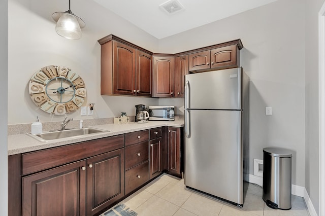 kitchen featuring stainless steel appliances, dark brown cabinets, sink, and light tile patterned floors