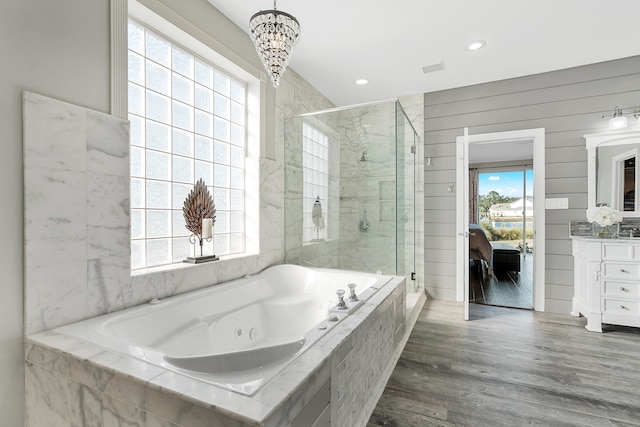 bathroom featuring an inviting chandelier, hardwood / wood-style floors, vanity, separate shower and tub, and wood walls