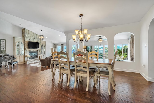 dining space with dark wood-type flooring, a fireplace, a healthy amount of sunlight, and vaulted ceiling