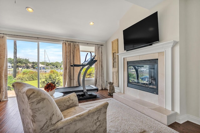 living room with a tiled fireplace, vaulted ceiling, and dark hardwood / wood-style flooring