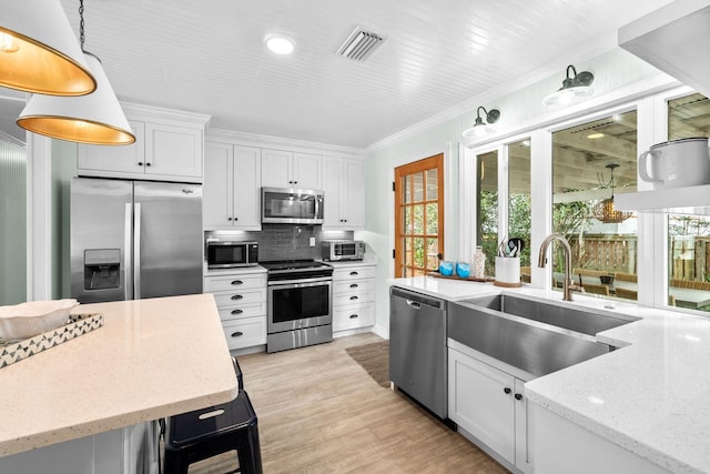 kitchen with light stone counters, white cabinets, tasteful backsplash, hanging light fixtures, and stainless steel appliances