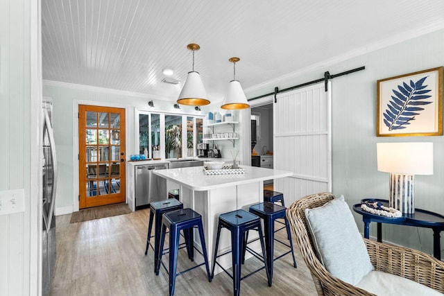 kitchen with appliances with stainless steel finishes, a kitchen bar, light hardwood / wood-style floors, and a barn door