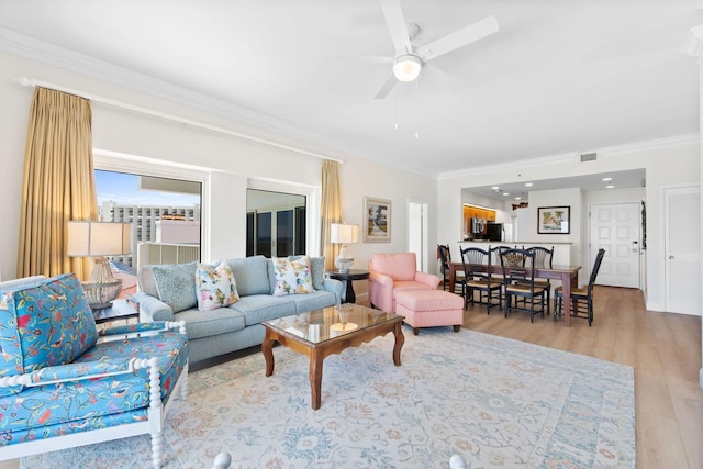 living room with light hardwood / wood-style flooring, ceiling fan, and ornamental molding