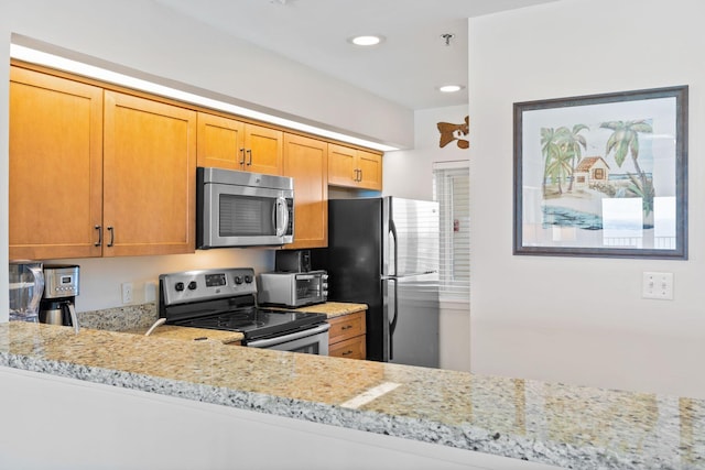 kitchen with light stone counters, kitchen peninsula, and stainless steel appliances