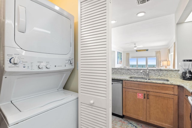 washroom featuring sink, stacked washer / drying machine, and ornamental molding