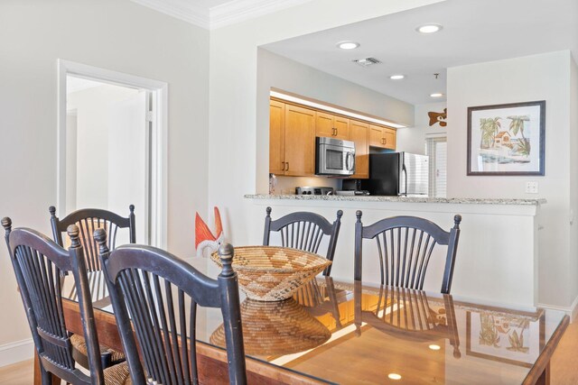 dining space with ornamental molding and light hardwood / wood-style floors