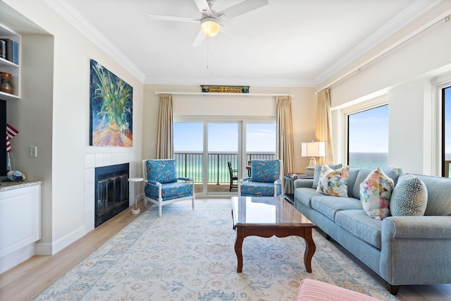 living room with light hardwood / wood-style flooring, a healthy amount of sunlight, ceiling fan, and a tiled fireplace