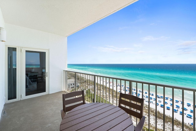 balcony with a water view and a view of the beach