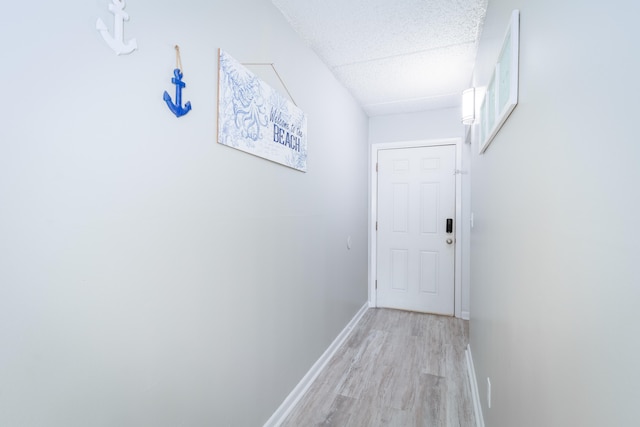 hall with a textured ceiling and light hardwood / wood-style floors