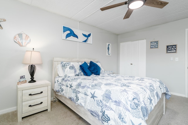 carpeted bedroom featuring a closet, ceiling fan, and a textured ceiling