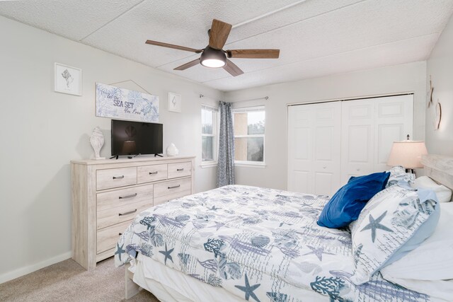 bedroom featuring light colored carpet, a closet, ceiling fan, and a textured ceiling