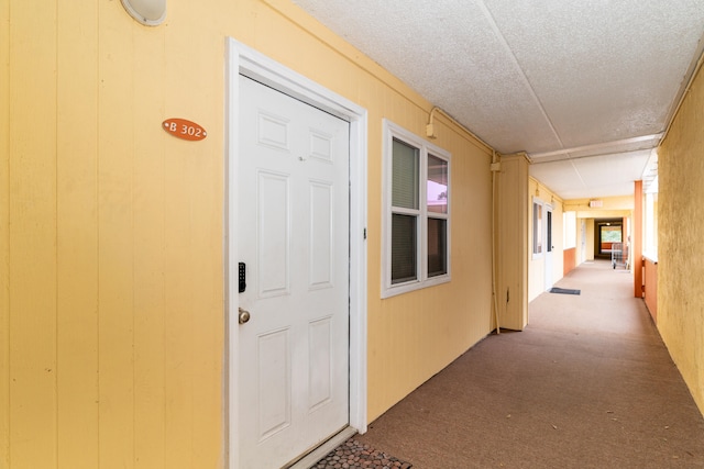 corridor featuring a textured ceiling and carpet