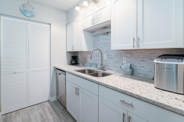 kitchen with white cabinets, light hardwood / wood-style flooring, sink, tasteful backsplash, and dishwasher