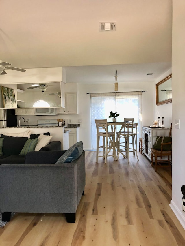 living room with ceiling fan, light hardwood / wood-style flooring, and sink