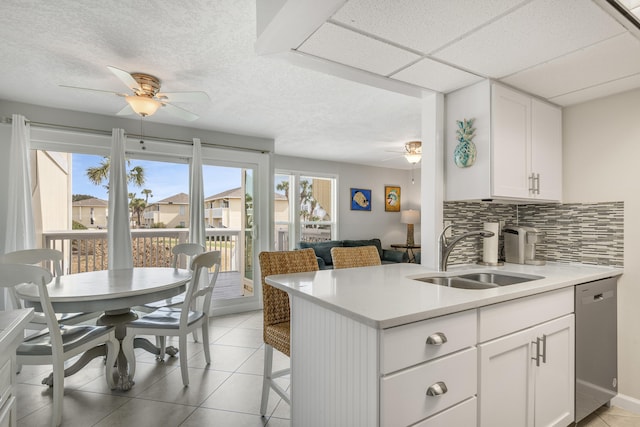 kitchen featuring dishwasher, tasteful backsplash, white cabinets, sink, and light tile floors