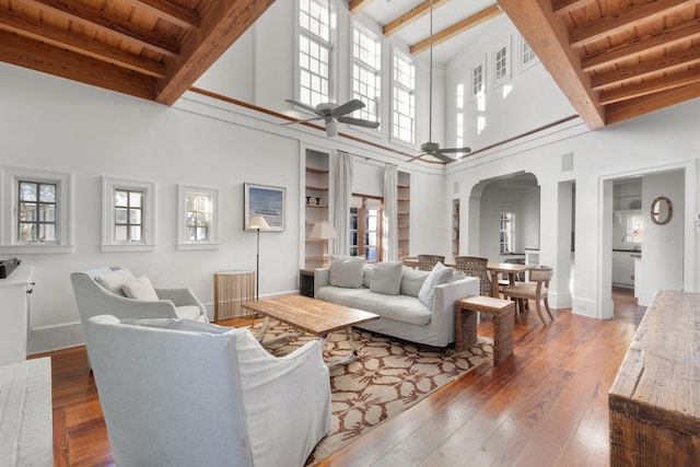 living room featuring wooden ceiling, ceiling fan, a high ceiling, beamed ceiling, and hardwood / wood-style floors