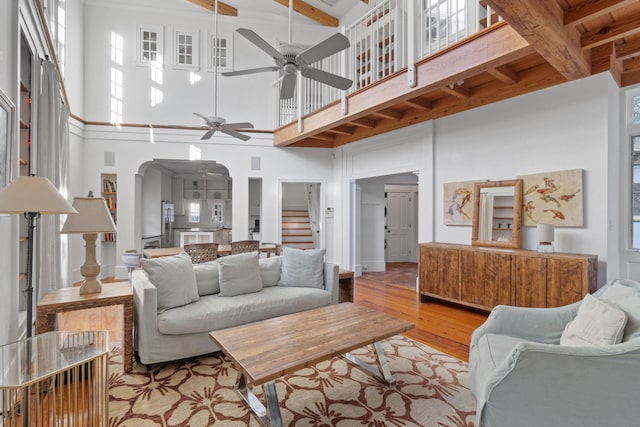 living room with ceiling fan, a towering ceiling, and light hardwood / wood-style flooring