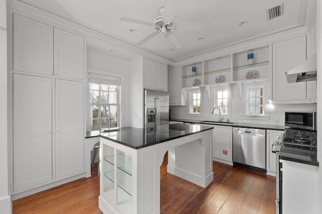 kitchen with a kitchen island, stainless steel appliances, white cabinetry, and hardwood / wood-style flooring