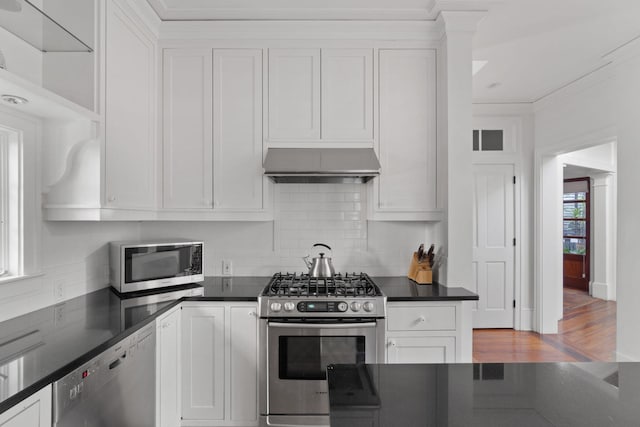 kitchen with wall chimney exhaust hood, light hardwood / wood-style flooring, stainless steel appliances, and white cabinetry