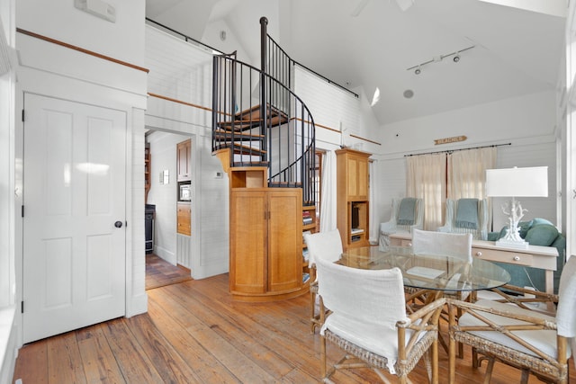 dining area with high vaulted ceiling, ceiling fan, light wood-type flooring, and track lighting