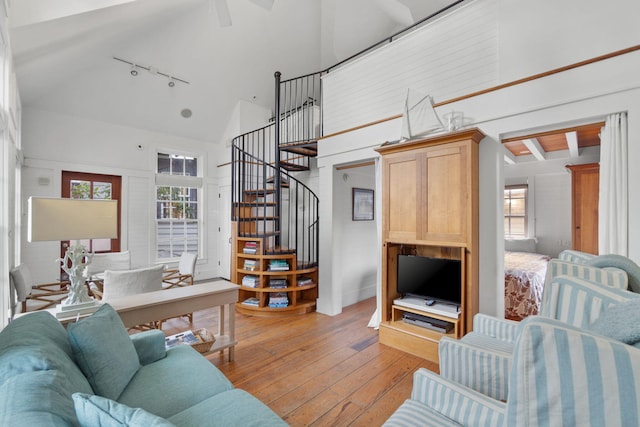 living room with rail lighting, light hardwood / wood-style flooring, beamed ceiling, and high vaulted ceiling